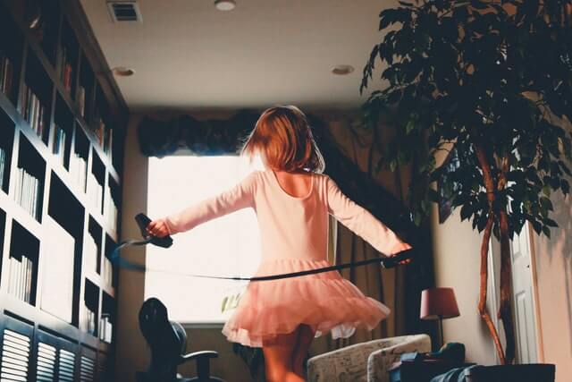 Mädchen im rosa Kleid springt fröhlich Seil in einer Wohnung