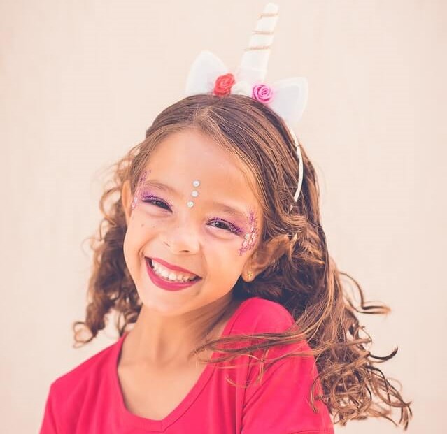 Fröhliches 7-jähriges Mädchen mit Kopfschmuck und Kinderschminke
